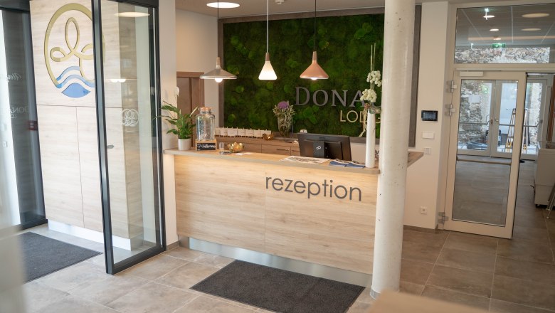 rezeption-und-gang, © Simon Kuntner Rezeption mit Holztheke und grüner Mooswand im Hintergrund.