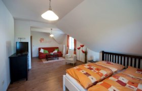 Gästezimmer, © Familie Rain Gemütliches Gästezimmer mit Doppelbett, Sofa, Fernseher und dekorativen Elementen.