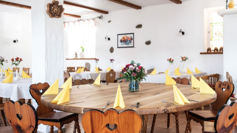 Stube mit Musikstammtisch, © Niederösterreich Werbung/Nadja Büchler Ein gemütlicher Raum mit Holztischen und -stühlen, gelben Servietten und Blumenarrangements.
