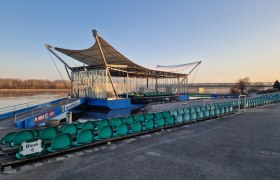 Donaubühne im Winter, © Donau Niederösterreich, K.Kancer Freiluftbühne mit leeren Sitzreihen am Flussufer bei Sonnenaufgang.