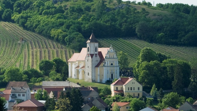 Jakobskirche, © Michael Himml Eine Kirche inmitten von Weinbergen und Häusern, umgeben von grünen Hügeln.