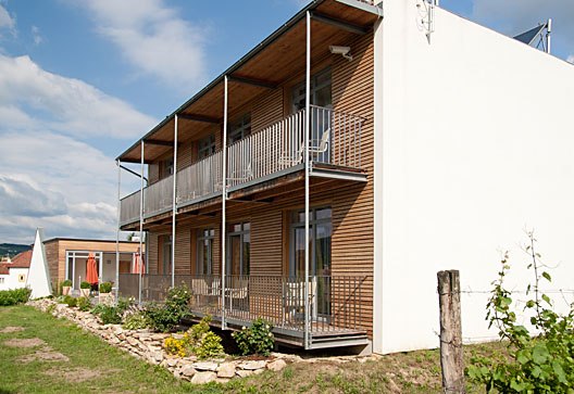 Aussenansicht, © Weinresidenz Sonnleitner Modernes Gebäude mit Holzfassade und Balkonen, umgeben von Garten.