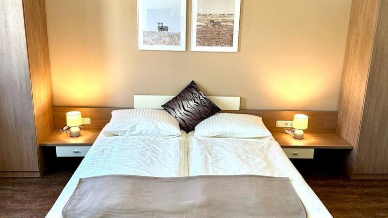 Familienzimmer, © Johnys Jungle Modern eingerichtetes Schlafzimmer mit Doppelbett, zwei Nachttischen und Wandbildern.