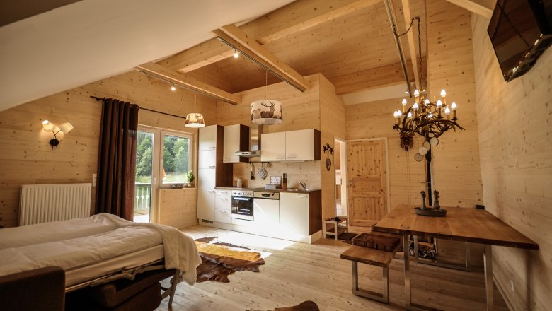 Steirer Apartment, © Stefan Zimprich Gemütliches Apartment mit Holzwänden, Küche, Esstisch und Bett.