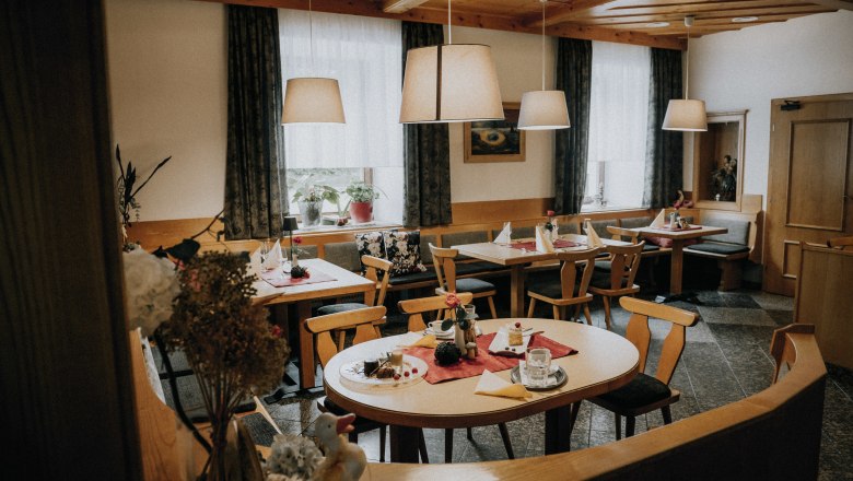 Schöne Stube, großer Gastgarten mit Nussbäumen, © Niederösterreich Werbung/Rita Newman Gemütlicher Gastraum mit Holzmöbeln, gedeckten Tischen und Hängelampen.