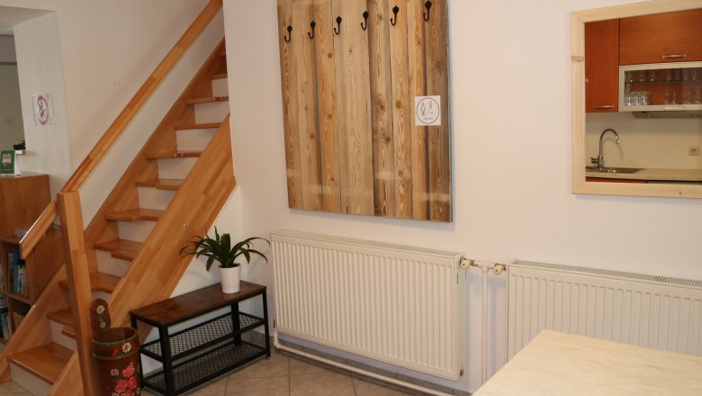 Garderobe Gaeste 6, © Gruber Claudia Innenraum mit Holztreppe, Garderobe, Pflanze und Küchenfenster.