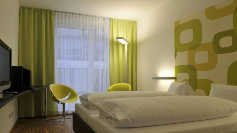 arte Hotel, © arte Hotel Modernes Hotelzimmer mit Doppelbett, grün-gelben Vorhängen und Wanddekor.