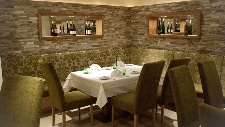 Restaurant Gartenhotel Pfeffel, © Alexander Pfeffel Elegantes Restaurant mit gedecktem Tisch und grünen Stühlen.