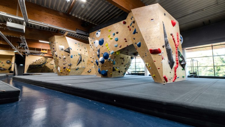 BigWall Bouldering, © thommy k Innenansicht einer Kletterhalle mit verschiedenen Kletterwänden und bunten Griffen.