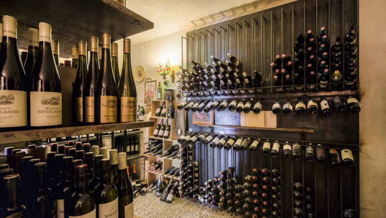 Weinkeller, © Lukas Kirchgasser Ein Weinkeller mit Regalen voller Weinflaschen, die ordentlich gestapelt sind.
