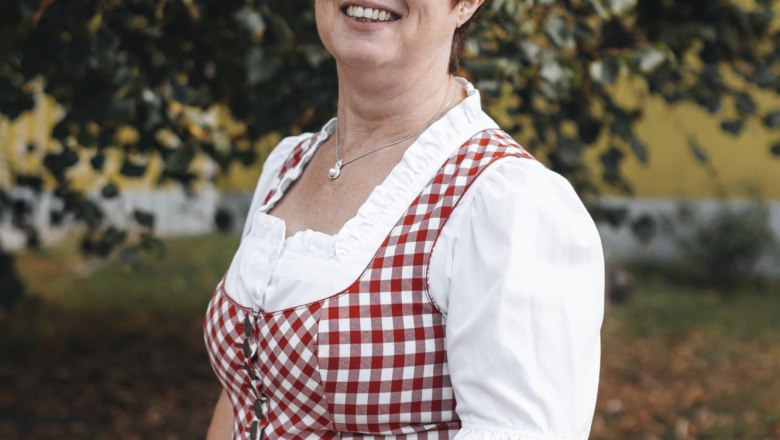 Wirtin: Anita Scheiterer, © Niederösterreich Werbung/David Schreiber Frau in traditioneller Tracht vor einem Baum im Freien.