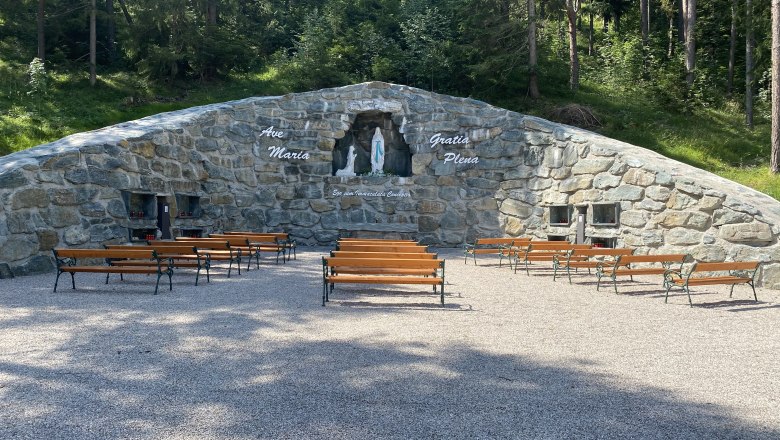 Lourdes Grotte Maria Schutz, © Wiener Alpen Steingrotte mit Marienstatue und Bänken davor im Freien.