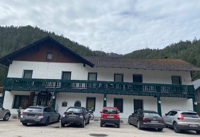 Gasthof Kreuzhof, © Wiener Alpen Ein zweistöckiges Gebäude mit grünem Balkon und geparkten Autos davor.
