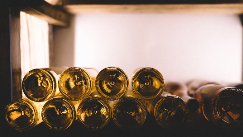 Gut gefüllter Weinkeller, © Niederösterreich Werbung/Mara Hohla Nahaufnahme von Weinflaschen in einem Regal, die horizontal gestapelt sind.