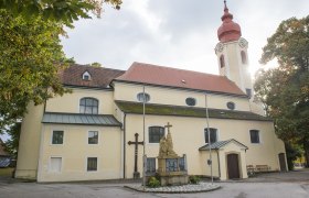 Pfarrkirche Heiligeneich, © Richard Marschik Pfarrkirche Heiligeneich mit Statue und Kreuz im Vordergrund.