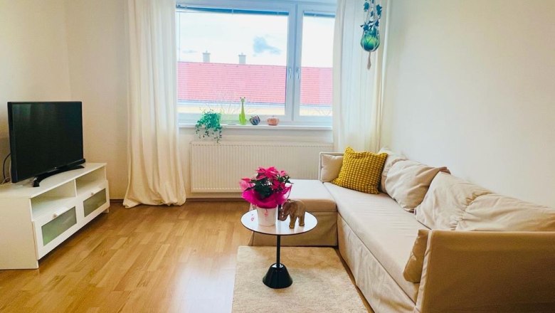 Wohnzimmer Ferienwohnung Café Frau Tinz, © Martina Lechner Helles Wohnzimmer mit Sofa, Couchtisch, Fernseher und Fenster mit Vorhängen.