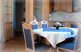 Ferienwohnung Stiefelbauer, © Fam. Stiefelbauer Essbereich einer Ferienwohnung mit Holzmöbeln und blauer Tischdecke.