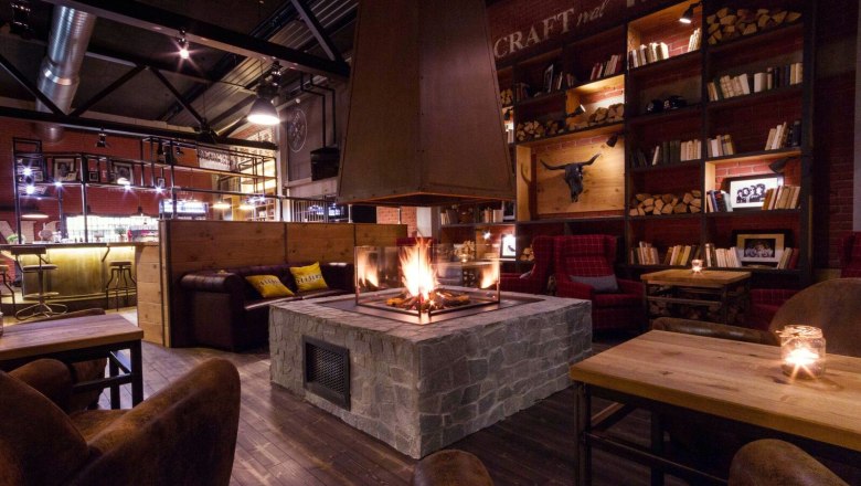 Living Room, © Derenko GmbH Gemütlicher Raum mit Kamin, Holzmöbeln und Bücherregalen.