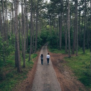 Paar von hinten fotografiert, geht entlang des Waldweges