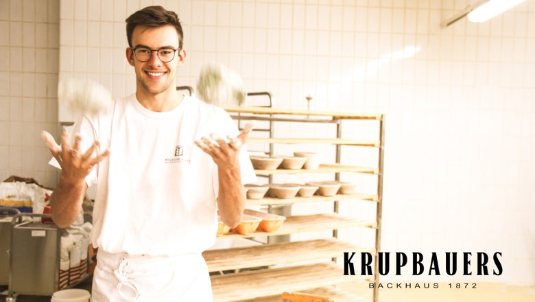 Backstube Krupbauers Backhaus 1872, Bruck/Leitha, © Krupbauers Backhaus 1872 Ein Bäcker jongliert mit Teigbällen in einer Backstube.