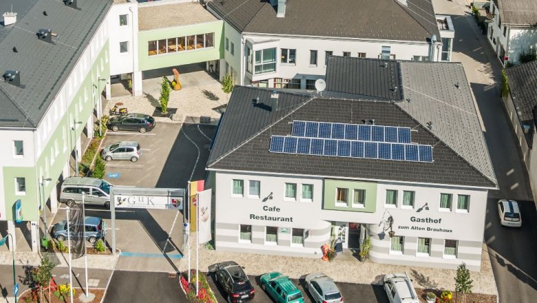 Gasthof zum Alten Brauhaus, © Markus Haslinger Luftaufnahme eines Gebäudekomplexes mit dem Gasthof zum Alten Brauhaus, Solarpanels auf dem Dach und mehreren geparkten Autos.