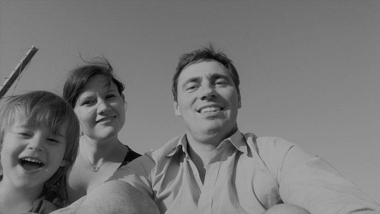 Familie Holzer, © Stephanie Holzer Schwarz-weiß Foto einer lächelnden Familie, bestehend aus einem Mann, einer Frau und einem Kind, die in die Kamera schauen.