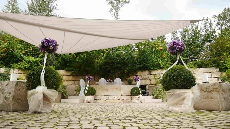 Hochzeit im Liebesgarten, DIE GARTEN TULLN, © DIE GARTEN TULLN Hochzeitsdekoration im Freien mit lila Blumen und weißen Stühlen.