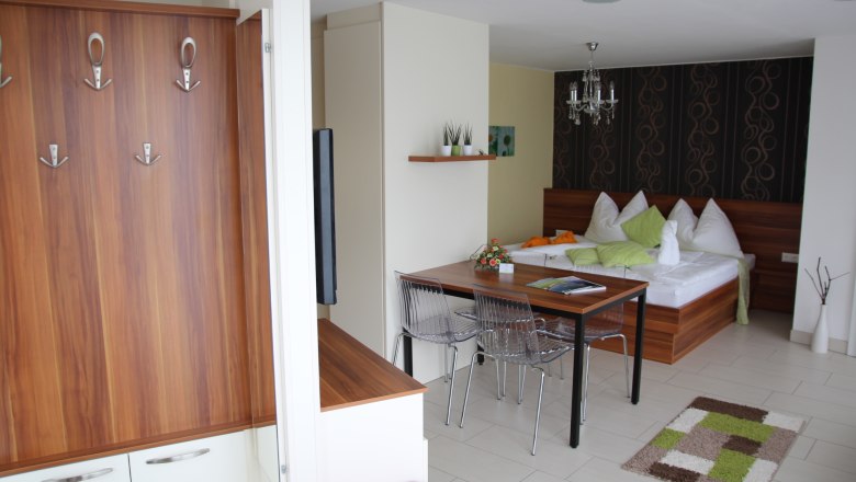 Gartenappartement Ybbs, © Georg Anker Modernes Appartement mit Holzmöbeln, Esstisch, Bett und dekorativen Elementen.
