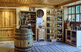 Ab Hof Laden Muthenthaler, © Florian Schulte Innenansicht eines rustikalen Weinladens mit Holzregalen und Weinfässern.