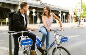 Nextbike Radverleih, © pixabay Zwei Personen lachen und sitzen auf Nextbike-Fahrrädern an einer Straßenecke.