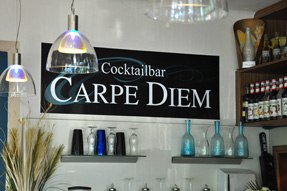 Carpe Diem_Schild, © Carpe Diem Innenansicht einer Bar mit einem Schild 'Cocktailbar Carpe Diem' an der Wand.