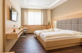 Gästezimmer, © Fam Breitenfelder / Podolsky Modernes Gästezimmer mit Doppelbett, Flachbildfernseher und Holzmöbeln.