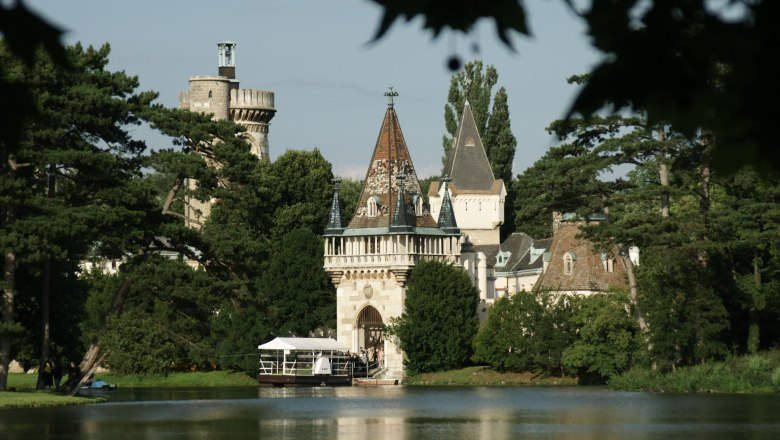 Laxenburg, © Laxenburg Schloss Laxenburg mit Türmen und Bäumen am Seeufer.