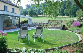 Garten auf der Lugerfarm, © Lugerfarm Garten mit Liegestühlen, Terrasse und Pflanzen auf der Lugerfarm.