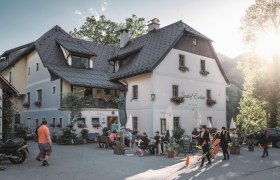 Gasthof Eschau, © Gasthof Eschau Ein traditionelles Gasthaus mit Menschen im Freien bei Sonnenschein.