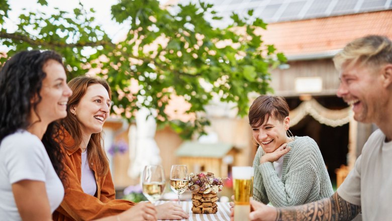 Mohnwirt Neuwiesinger, © © Waldviertel Tourismus, Gerhard Wasserbauer Vier Personen sitzen lachend an einem Tisch im Freien mit Getränken.