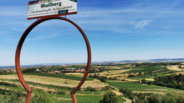 Blick durchs Schlüsselloch, © Weinstraße Weinviertel Landschaft mit Weinbergen und einem Schild mit der Aufschrift 'Mailberg Weinstraße Weinviertel'.