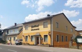 Gasthof Mühlendorfer, © Wiener Alpen Ein gelbes Gebäude mit der Aufschrift 'Gasthof Mühlendorfer' an einer Straße.