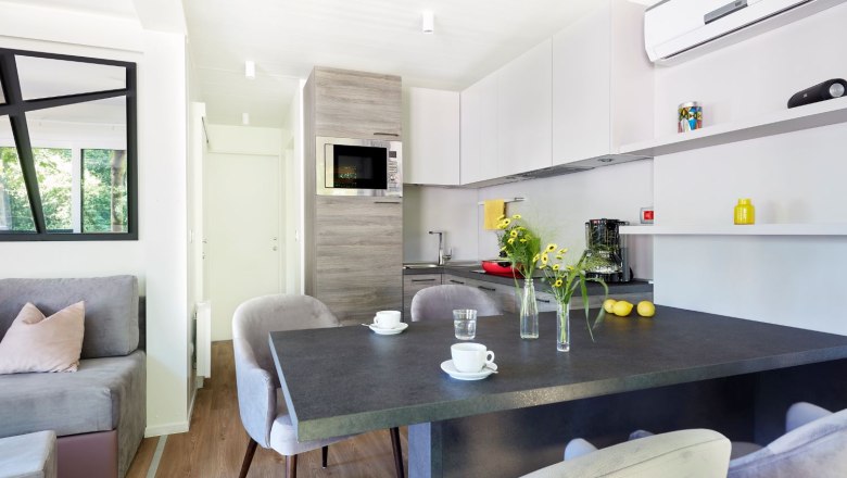 TDR-Mobilhome Essplatz, © Campingplatz Tulln Esstisch Mobilheim innnen mit Blumen und Tassen