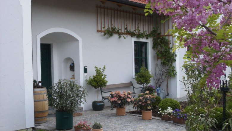 Landhaus Rossatz, © Landhaus Rossatz Eingang eines Landhauses mit blühenden Pflanzen und einem Fass.