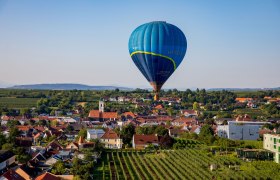 Ballontage Krems-Langenlois 2019 - Ballonfahrt über Langenlois, © Jürgen Übl Heißluftballon über einer Stadtlandschaft mit Weinbergen und Häusern.