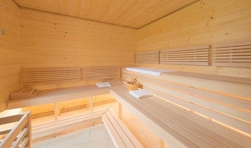 Sauna im Wellnesspavillon, © Elisabeth Samek Innenansicht einer modernen Sauna mit Holzbänken und Handtüchern.