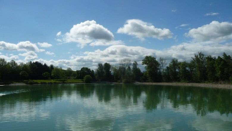 Ebersdorfer See, © zVg Gemeinde Ober-Grafendorf Ein ruhiger See mit Bäumen und Wolken, die sich im Wasser spiegeln.