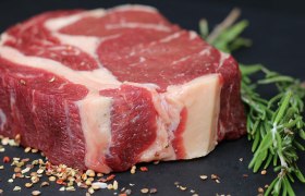 Steak, © unbekannt Ein rohes Steak auf einer dunklen Platte mit Gewürzen und Kräutern dekoriert.