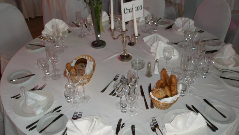 Partyservice Parzer-Reibenwein, © Parzer-Reibenwein Eleganter, gedeckter Tisch mit weißen Tischdecken, Kerzenständer und Brotkörben.