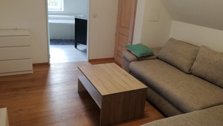 Ecksofa mit Bettfunktion, © Günter Lammer Wohnzimmer mit Ecksofa, Couchtisch und Blick ins Badezimmer.