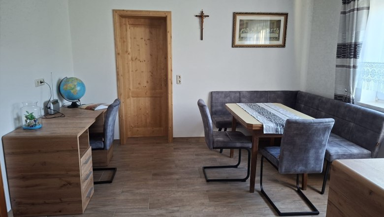 Essbereich, © Ferienwohnung Penz Stolzenthal, Fotograf Hermine Penz Esszimmer mit Holztisch, grauen Stühlen, einem Schreibtisch mit Globus und einem Kreuz an der Wand.