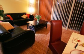 Ferienwohnung Familie Pichler, © Familie Pichler, weinfranz.at Gemütliches Wohnzimmer mit Ledersofas, Couchtisch, Blumenstrauß und Esstisch mit Obst.