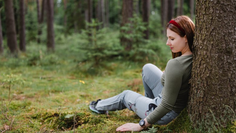 Achtsamkeit im Heilwald Göttweig, © Alexander Pfeffel Photography Frau lehnt an einem Baum im Wald.