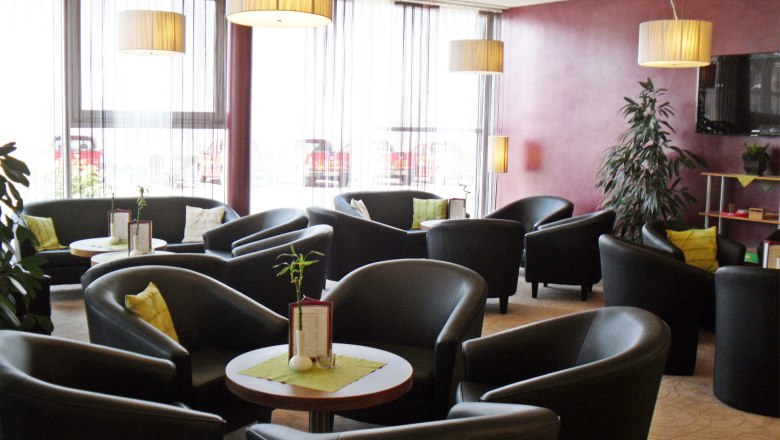 Lounge, © Römerhof Moderne Lounge mit schwarzen Sesseln, runden Tischen und großen Fenstern.